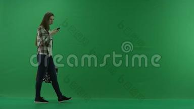 带包的女孩从右到左，在绿色屏幕上借助<strong>手机</strong>聊天